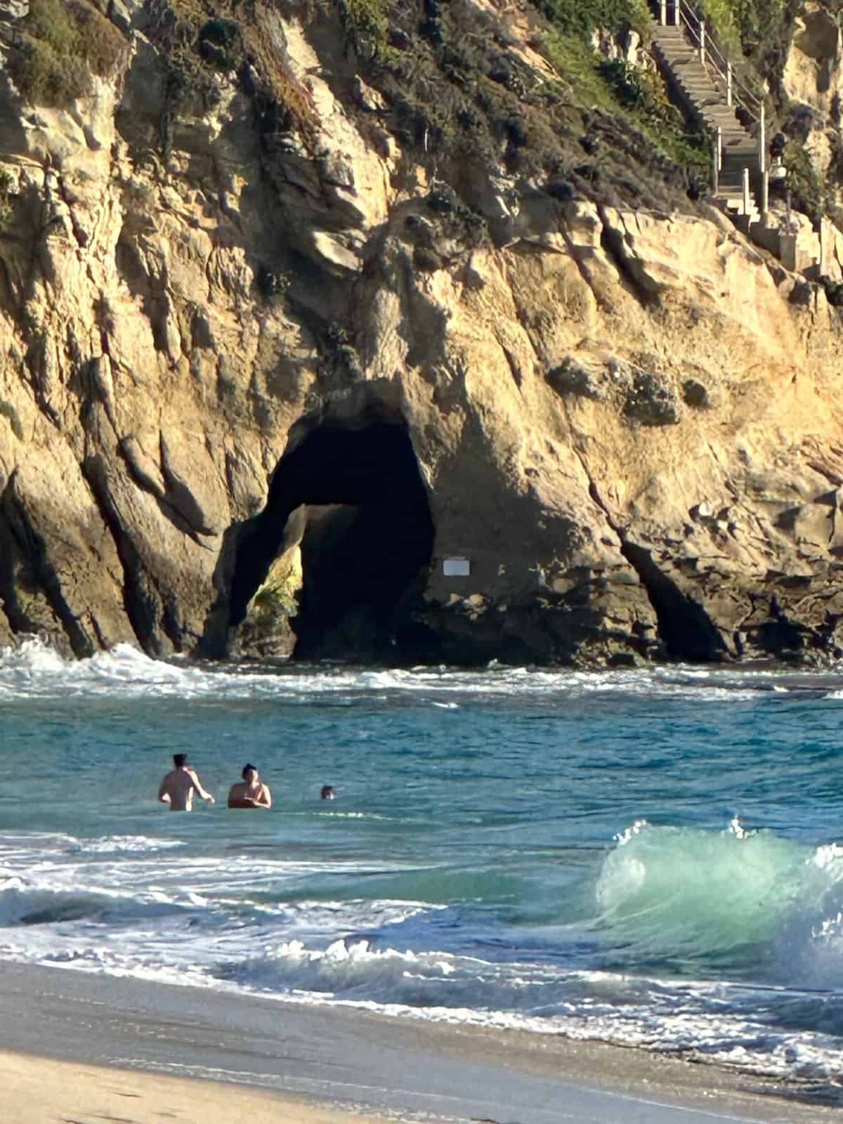 people in the water in thousand steps beach near the cave