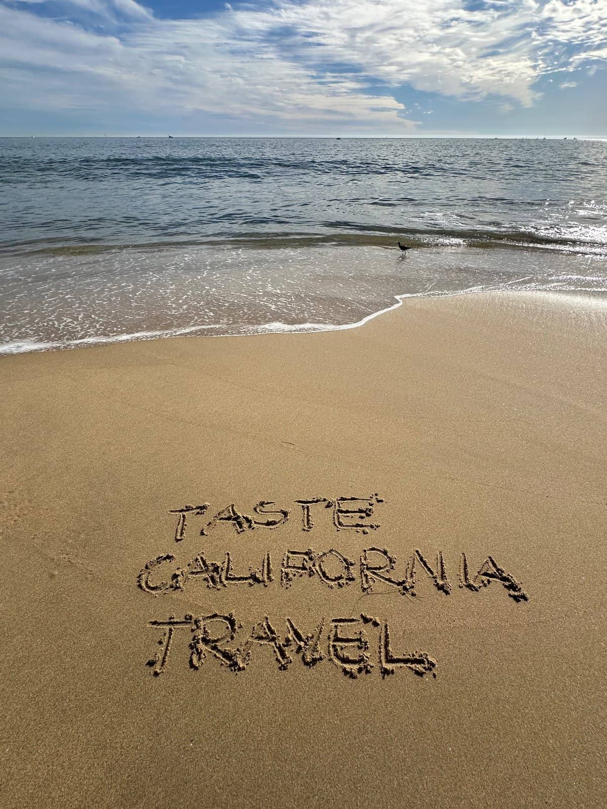 Taste California Travel written on the sand by the beach